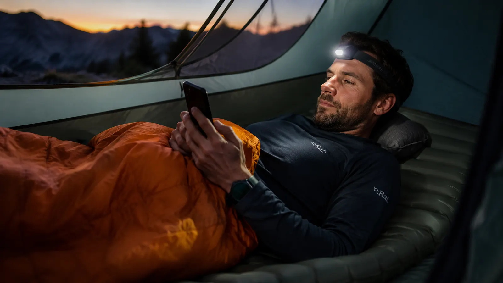 Camper inside tent reading a book with sleeping pad inflated and pillow positioned, relaxed before sleep